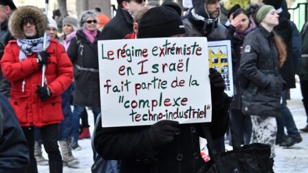 Une manifestation à Montréal pour Palestine. Des manifestants tiennent une pancarte sur laquelle il est écrit "Le régime extrémiste en Israël fait partie de la complexe techno-industriel".